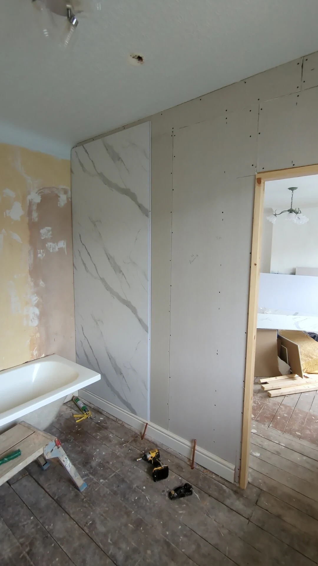 First PVC bathroom wall panel being set plumb in a Doncaster ensuite next to bare boarded wall