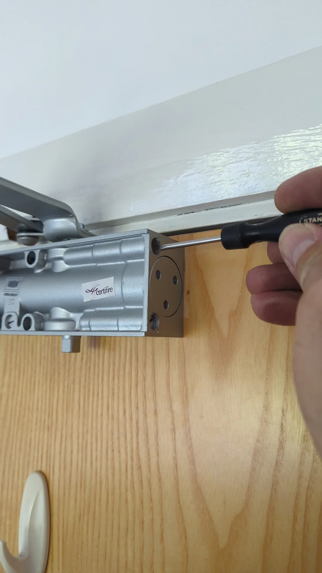 Adjusting the latch speed on a newly fitted overhead door closer with a screwdriver