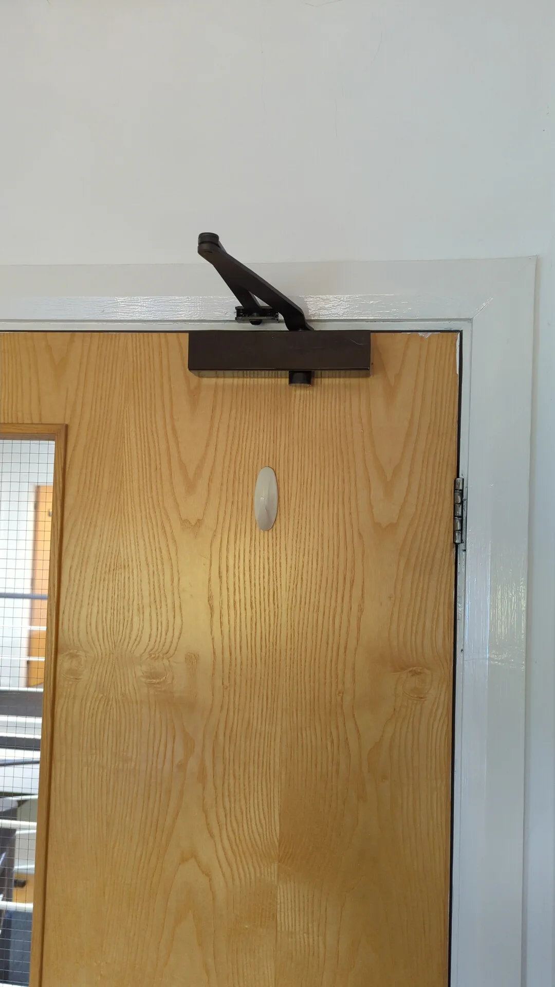 Failed overhead door closer on an office door before replacement