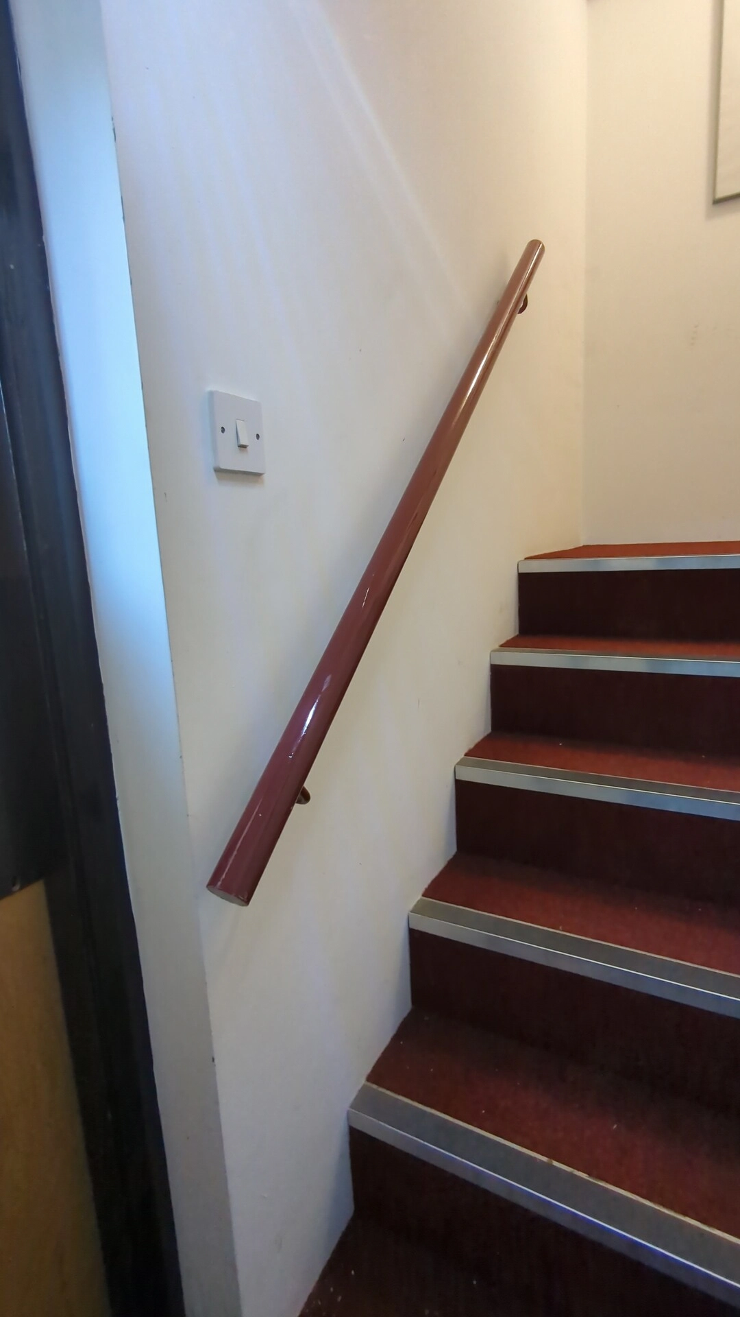 Timber staircase handrail refitted and secured back to the wall on a commercial staircase