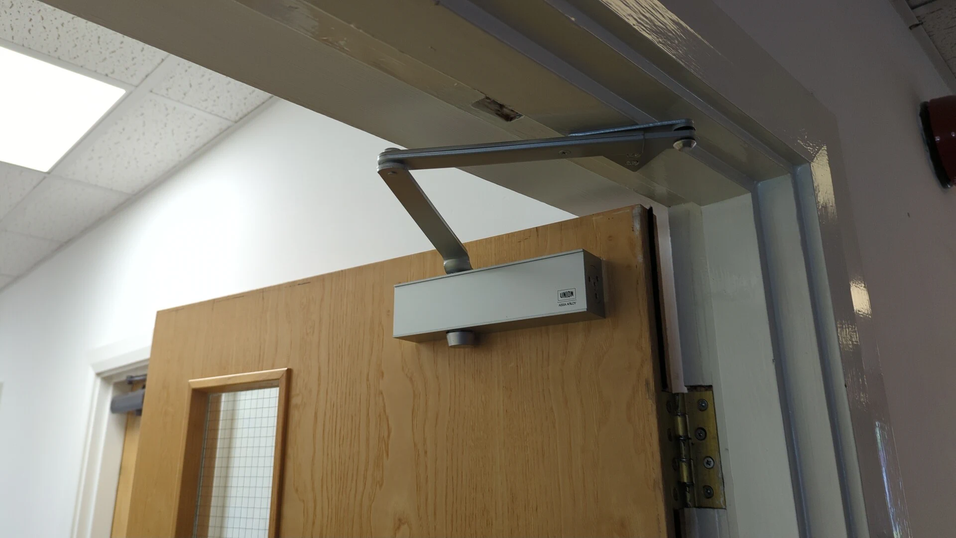 Replacement overhead door closer and arm fitted above an office door
