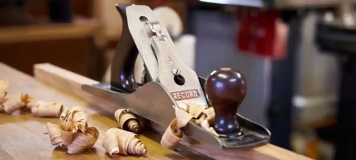 A traditional hand plane and fresh wood shavings on a bench in the Heritage Joiners workshop
