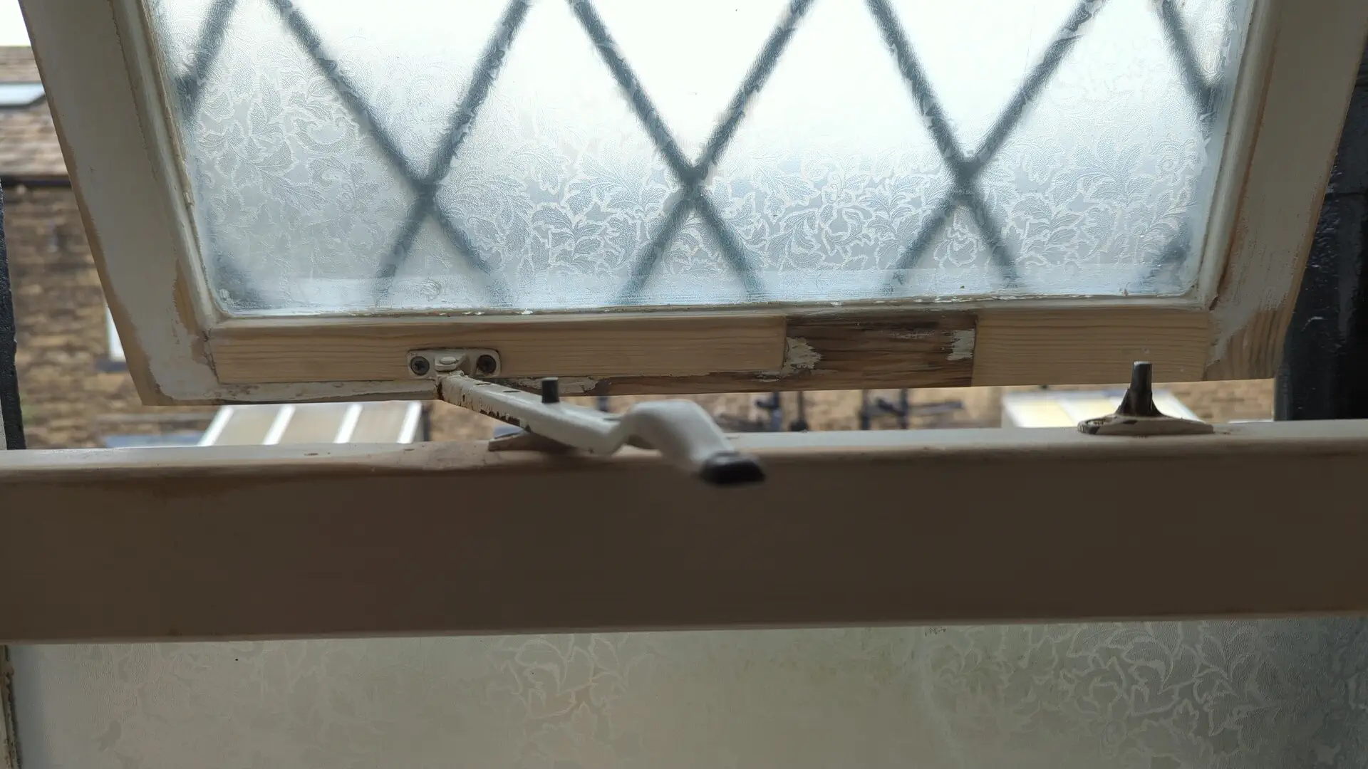 Repaired casement window refitted and opening on its stay, new timber in the rail visible before decoration