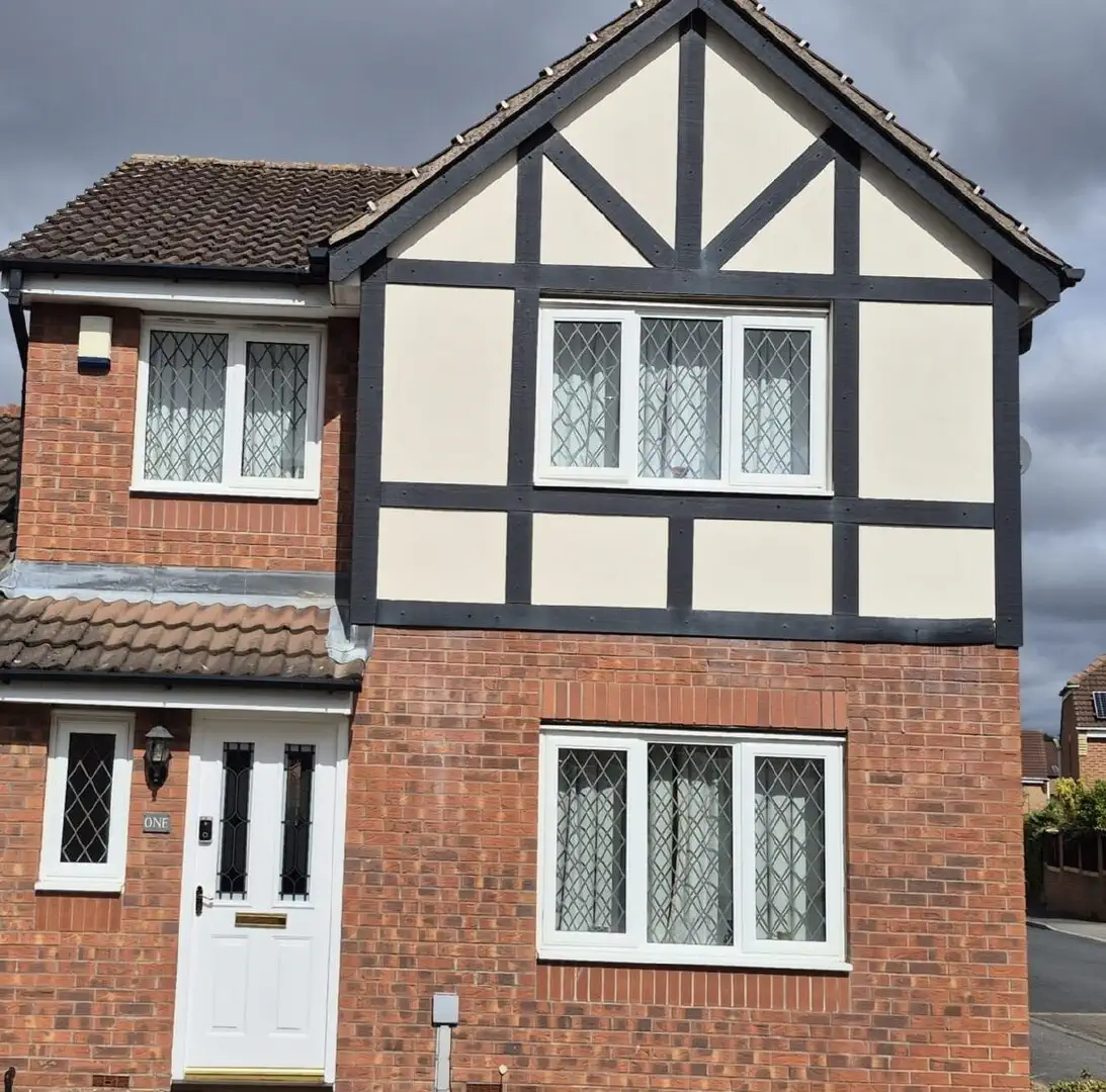 Mock-Tudor boarded frontage with cream render panels above brickwork before the board was replaced