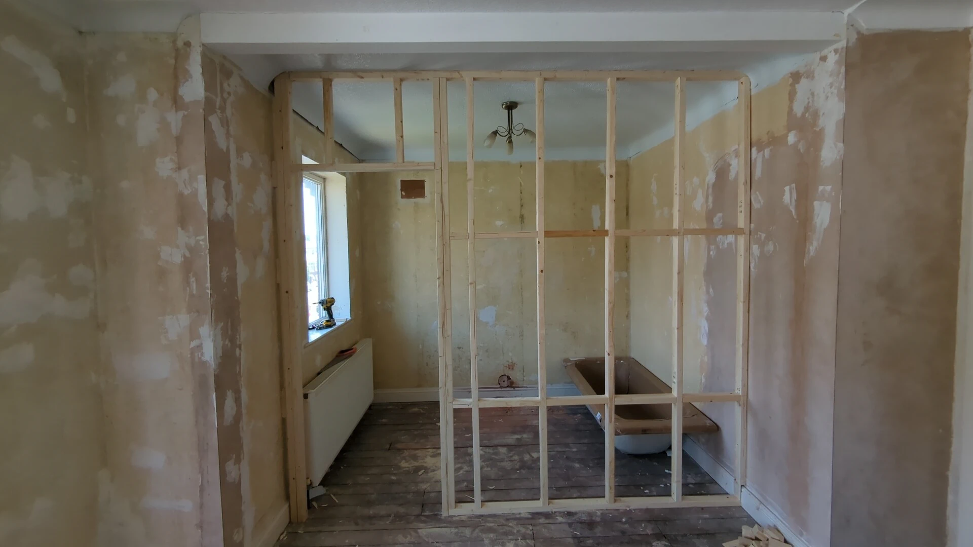 Timber stud partition frame with door studs and noggins in a stripped-back room