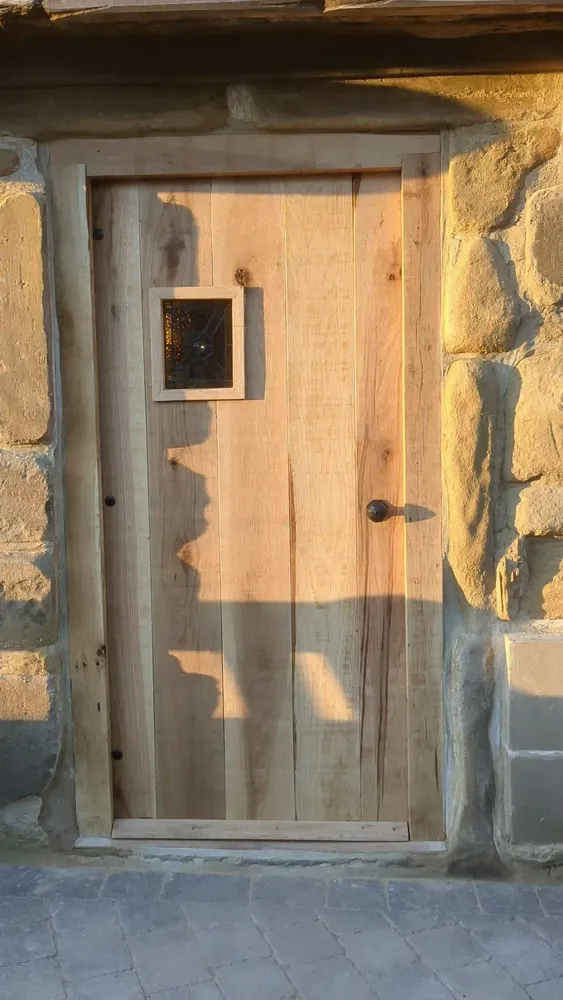 Bespoke solid oak ledged and braced front door with a small leaded glazed panel, hung in a stone opening at The Counting House