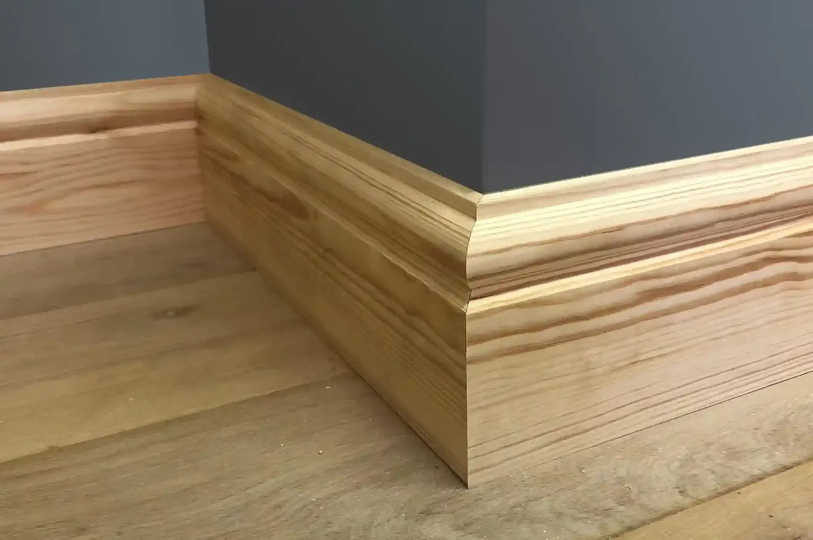 Torus profile timber skirting board scribed into a corner above a wood floor